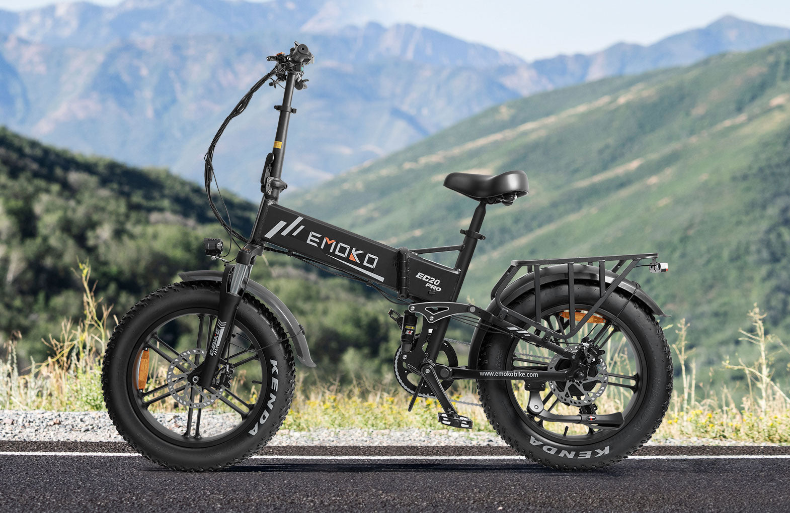 Black EMOKO EC20 Pro electric bike with fat Kenda tires on road with mountain background
