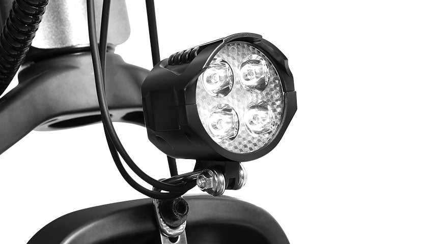 Close-up of black LED bike headlight mounted on electric scooter against white background